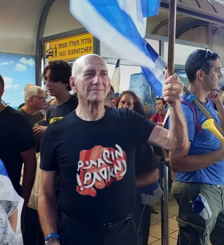 אהוד אולמרט מפריע לטסים לחול בנתבג עם חולצת מושחתים הביתה 3-7-2023